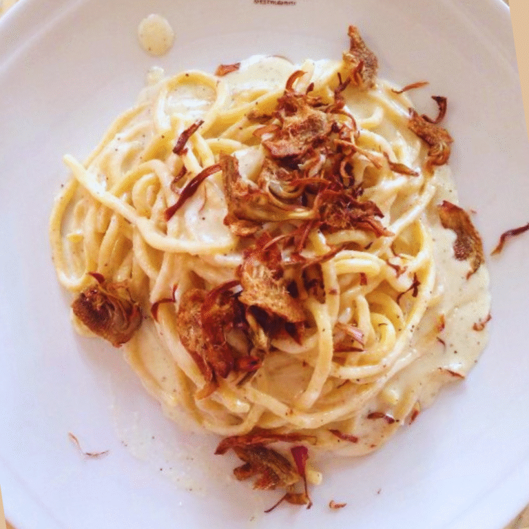 Tonnarello cacio e pepe con carciofo fritto, fotografato dall'alto nel piatto bianco