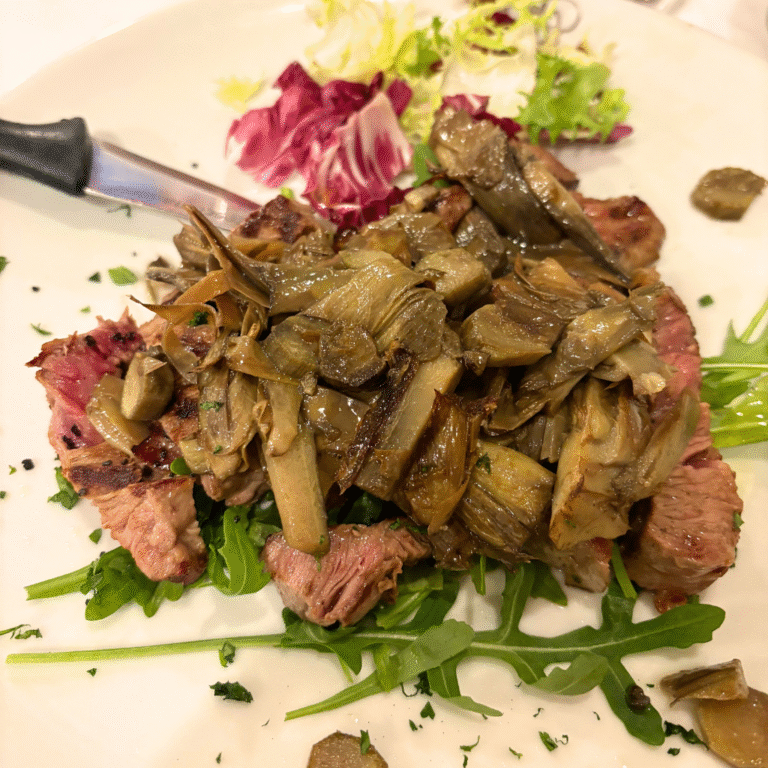 Tagliata di manzo con carciofi su rucola, servita a La Cabana